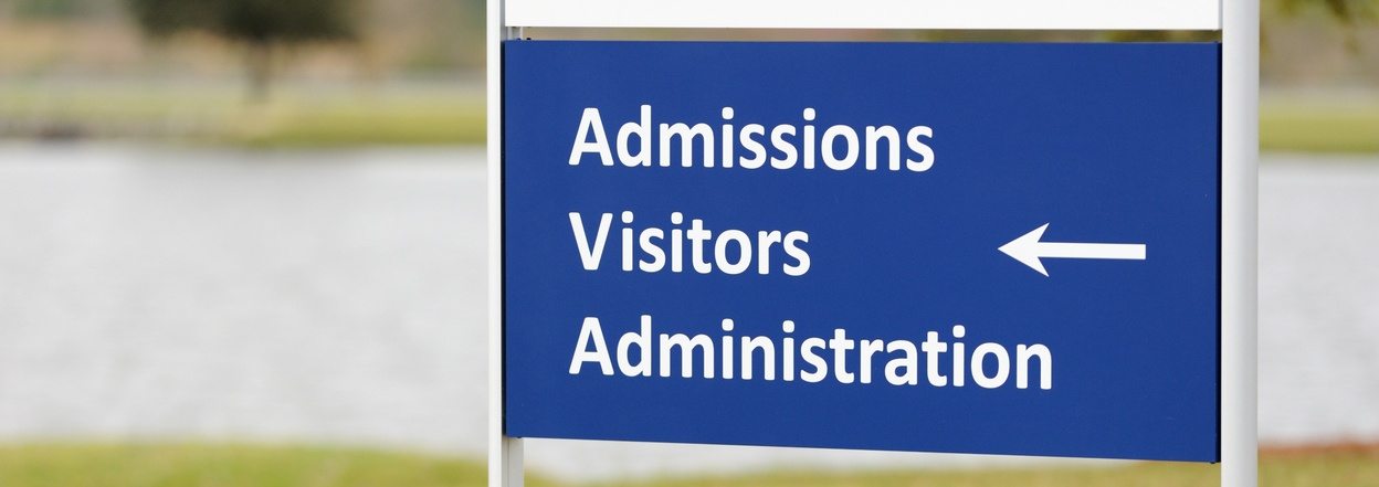 Sign reading "Admissions Visitors Administrators" with an arrow pointing left