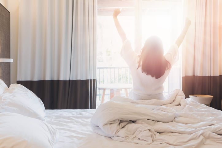 A woman waking up with the sunrise in a hotel room