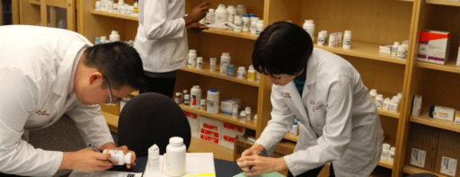 Northeastern Pharmacy students in handling prescription bottles in a clinic